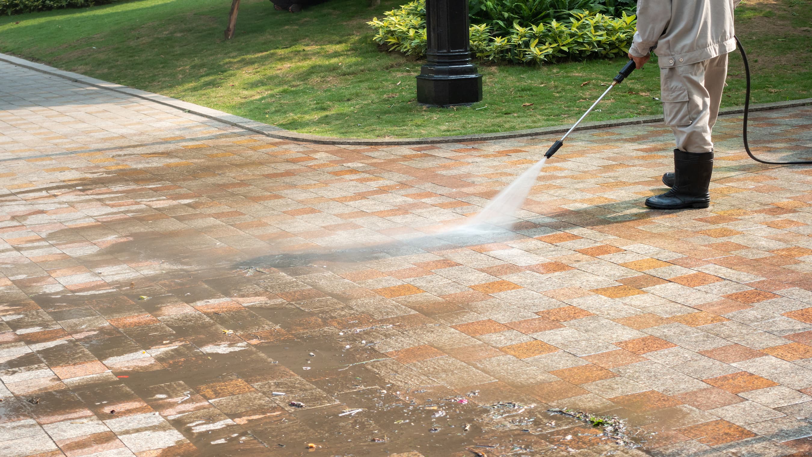 Man pressure-washing a multicolored stone walkway